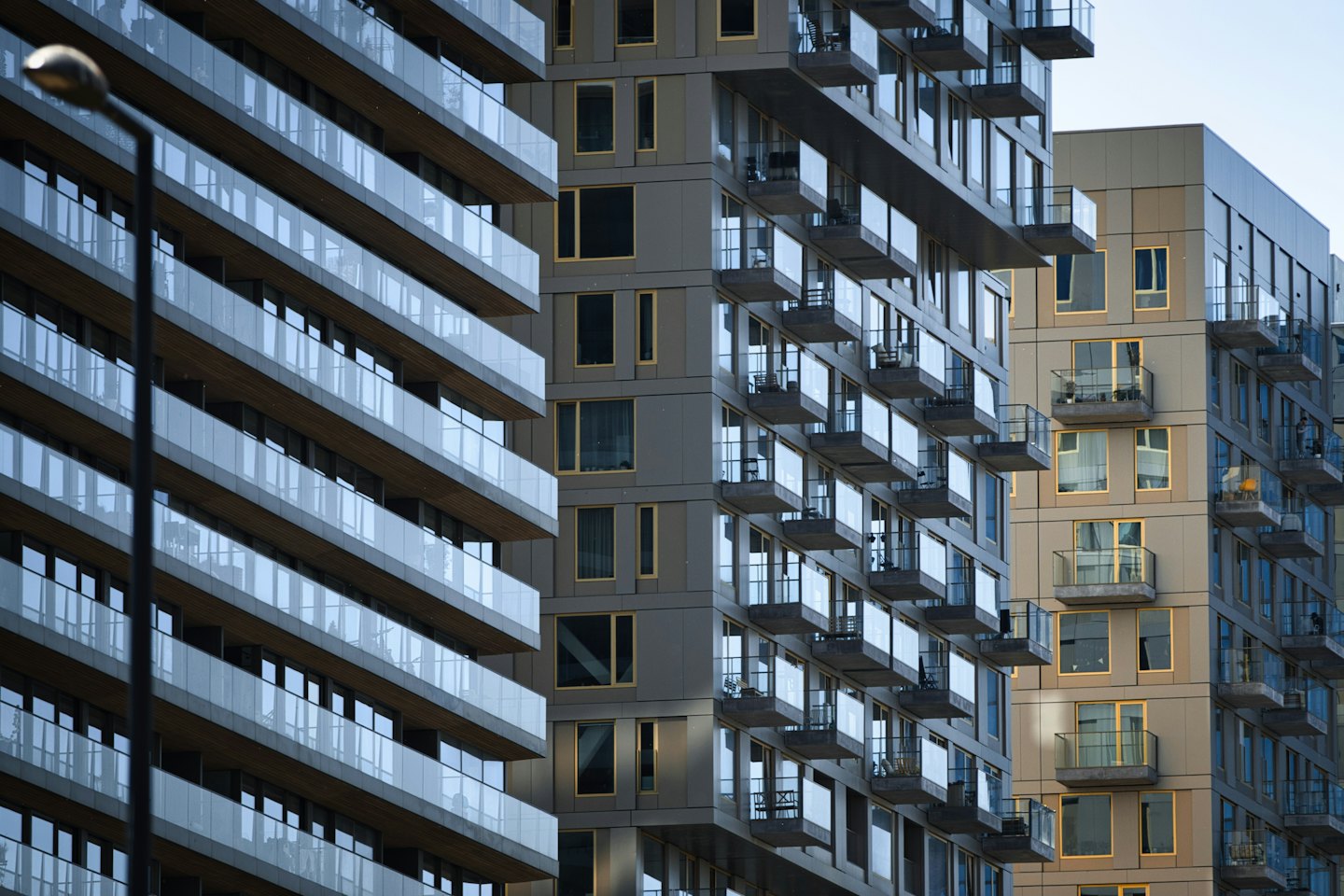 Modern apartment buildings featuring glass windows and many balconies.