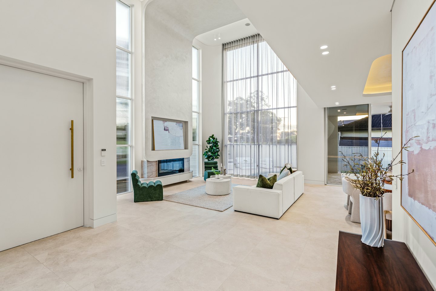 Spacious living room with white sofa and green chairs.